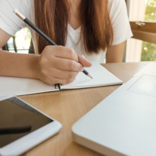 Frau sitzt vor einem Ringbuch mit Stift