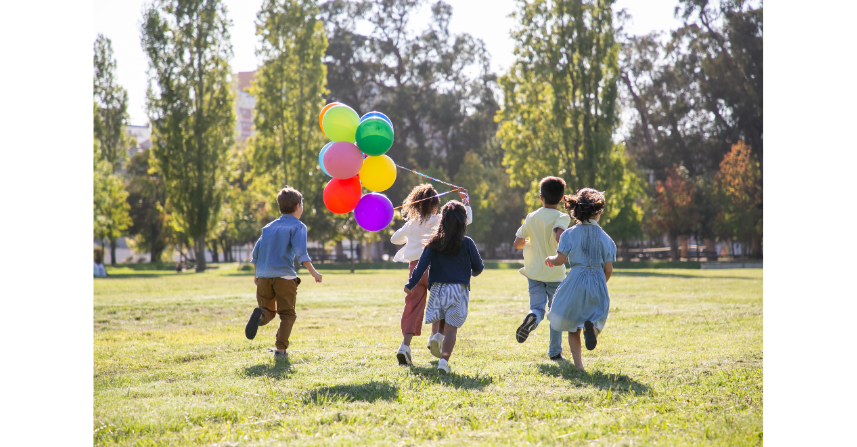 Kinder spielen mit Luftballons auf der grünen Wiese